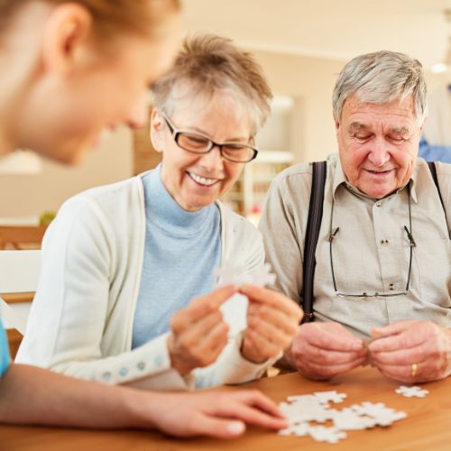 Allied-Health-Assistant-helping-with-seniors-making-a-puzzle
